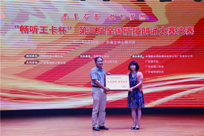 中国聋人协会副主席范宜涛(左)向广东省立中山图书馆副馆长李毅萍(右)